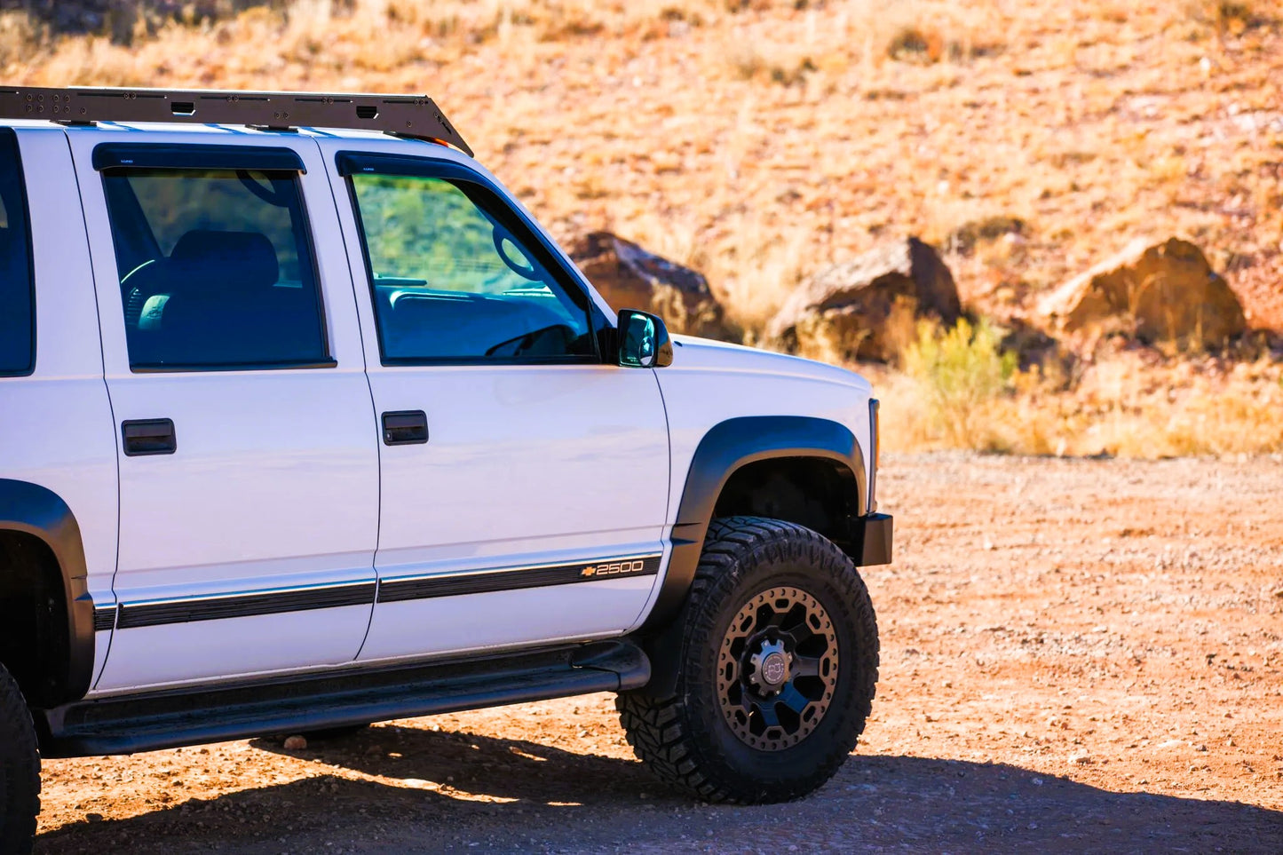 1992-1999 Chevrolet Suburban with roof rack  and Winch Bumper from Baseline Overland. White with black rims fender flares 33 inch tires